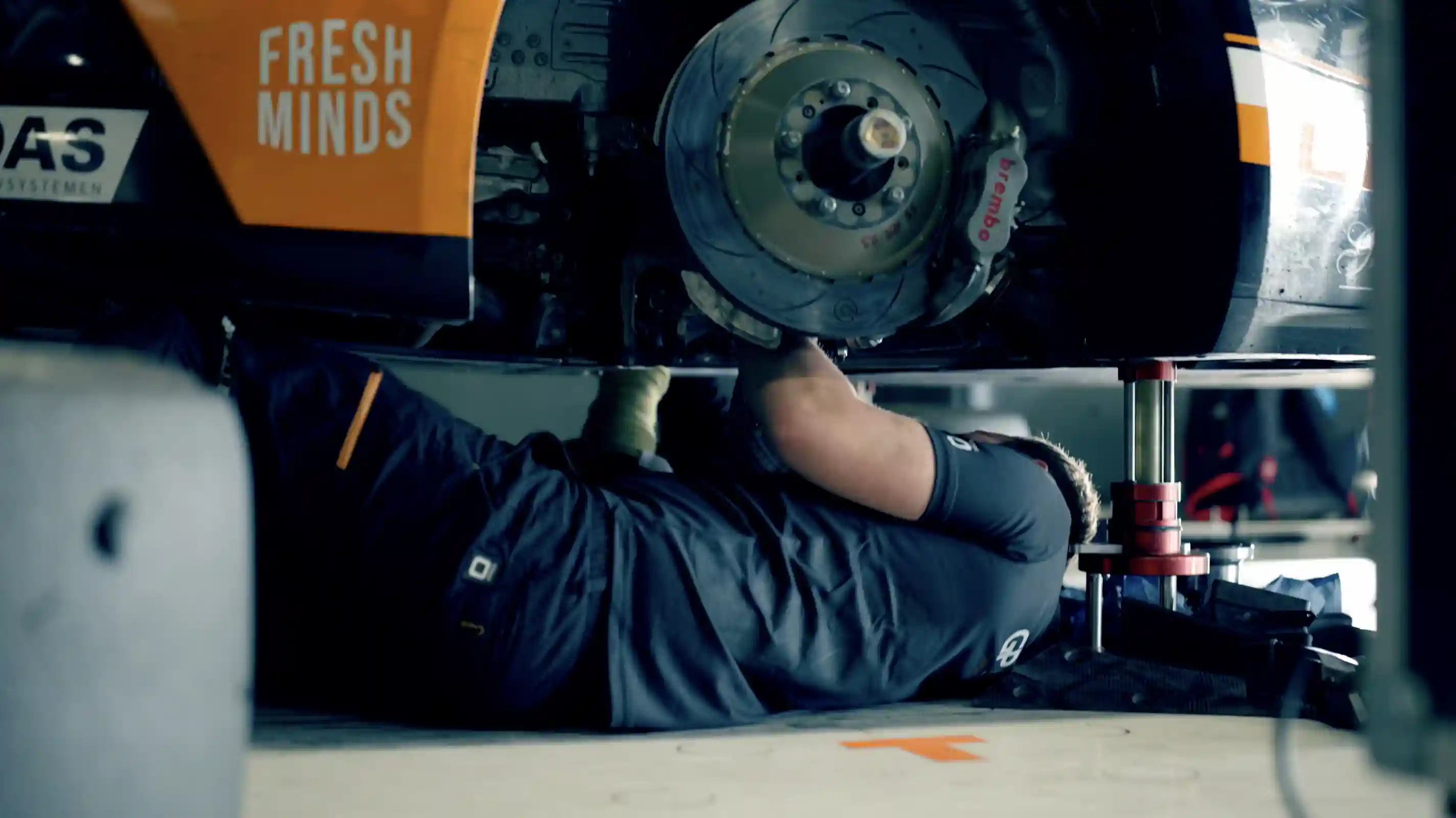 Race mechanic under a car, working on crucial repairs to optimize performance and speed. Precision and maintenance are key in motorsports.