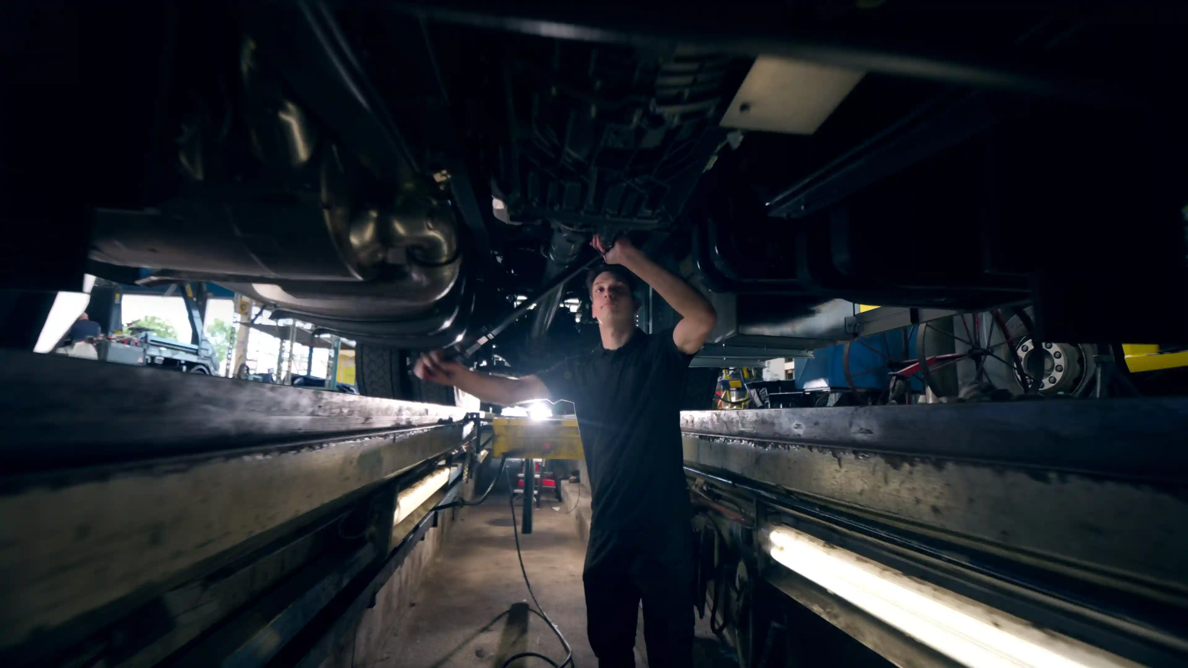 Mechanic under a truck performing essential repairs to keep the vehicle running safely and efficiently. 