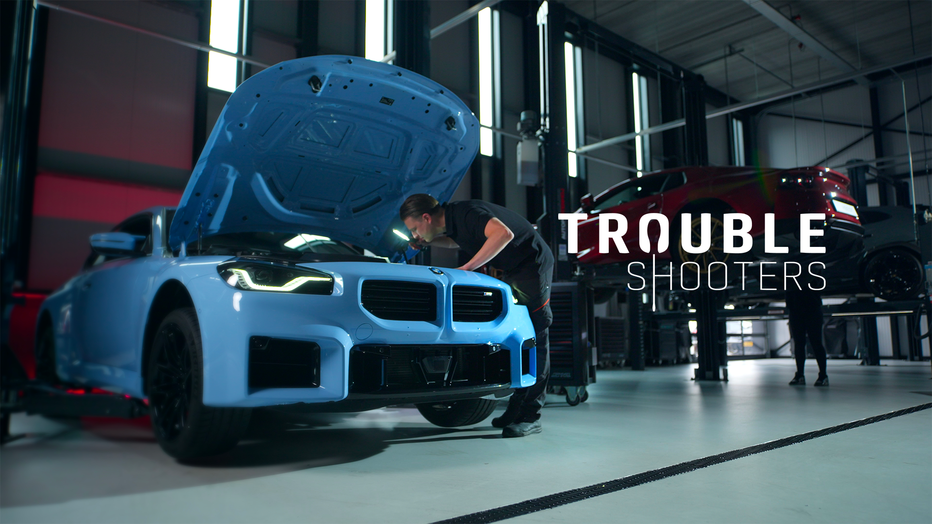 Mechanic shining a light into an M5, inspecting the engine for any issues. Detailed checks are essential for high-performance vehicles like the M5.